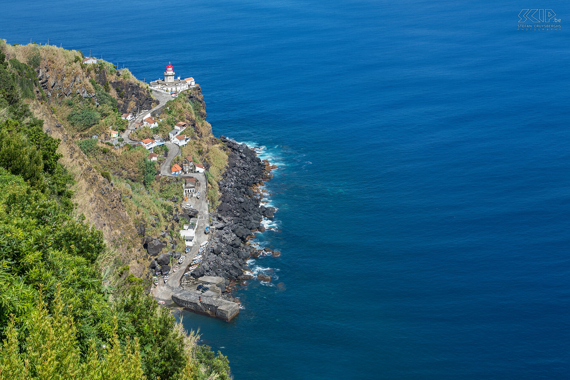 Lighthouse of Ponta do Arnel View of the lighthouse Farol Ponta do Arnel and the fishing harbor of Porto de Pescas in region of Nordeste. Stefan Cruysberghs